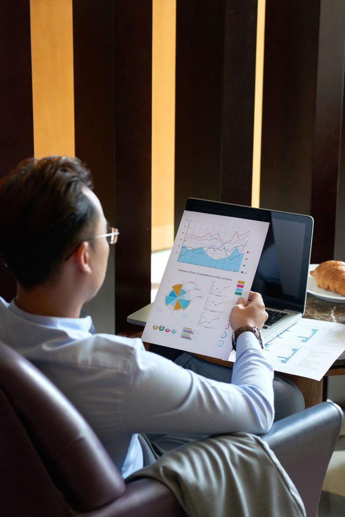 rear-view-man-seated-armchair-cafe-analyzing-diagrams-charts-before-presentation
